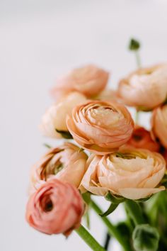 a bunch of pink flowers are in a vase on a table with white wall behind it