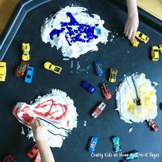 two children are playing with toys on a black tray that is covered in white frosting