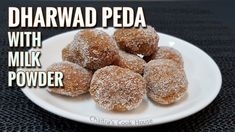 powdered sugar coated doughnuts on a white plate with the words dharwadd peda