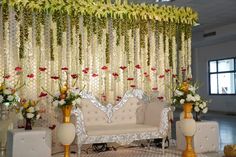 a white couch sitting in front of a wall covered with flowers and greenery on top of it