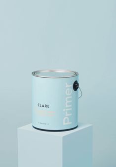 a can of primer paint sitting on top of a white block against a blue background