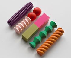 four different colored plastic objects sitting next to each other on top of a white surface