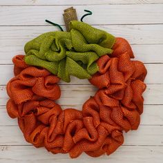 an orange and green mesh wreath on a white wooden surface