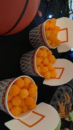 three buckets filled with orange candies on top of a basketball court tablecloth