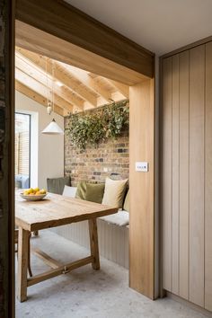 a wooden table sitting under a window next to a wall filled with plants and fruit