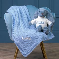 a blue chair with a teddy bear on it and a knitted blanket that says luke