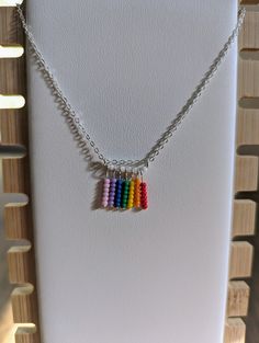 Welcome to our little corner of the internet, where we create unique and beautiful jewelry pieces made with love and care by queer hands. Our newest listing, the silver necklace with rainbow fringe pendant, is perfect for anyone looking for a subtle way to show their queer pride. Crafted with high-quality materials, this necklace features a beautifully designed silver pendant that is both elegant and understated. The pendant is adorned with a colorful fringe of rainbow hues, creating a gorgeous contrast that is sure to turn heads. As a queer-owned independent small business, we take great pride in creating jewelry that reflects our values and experiences. By purchasing this necklace, not only will you be adding a stunning piece to your collection, but you will also be supporting a queer ar Rainbow Sterling Silver Dangle Jewelry, Handmade Rainbow Necklaces For Everyday, Handmade Rainbow Necklaces For Everyday Wear, Handmade Rainbow Necklace For Everyday, Multicolor Sterling Silver Dangle Necklaces, Multicolor Sterling Silver Dangle Necklace, Rainbow Dangle Jewelry With Tiny Beads, Ornate Multicolor Beaded Sterling Silver Jewelry, Multicolor Sterling Silver Jewelry With Tiny Beads