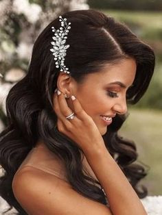 a woman wearing a wedding dress and holding her hand to her face, with flowers in the background