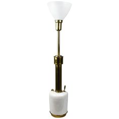 a lamp that is on top of a white object with a gold base and glass shade