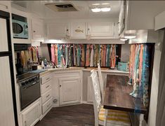 a kitchen with white cabinets and lots of colorful scarves hanging on the wall above the stove