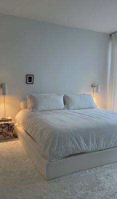 a large white bed sitting in a bedroom next to two lamps on either side of the bed