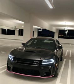 a black car is parked in a parking garage with pink trimming on the hood