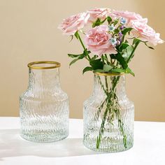 two glass vases with pink flowers in them