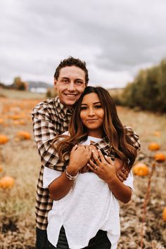 a man and woman hugging in a field full of pumpkins