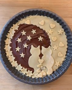 a pie with chocolate frosting and hearts in the shape of cats on it's side