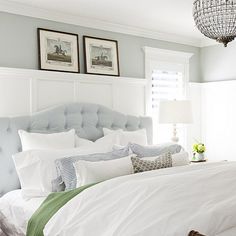 a white bed sitting in a bedroom next to two pictures on the wall above it