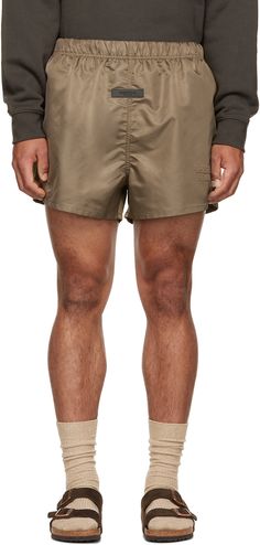 Nylon satin shorts. · Concealed bungee-style drawstring at elasticized waistband · Two-pocket styling · Rubberized logo patch at front · Logo flocked at front · Taffeta lining Please note that this item may not be shipped within the EU. Supplier color: Wood Nylon Shorts, Satin Shorts, Fear Of God Essentials, Fear Of God, Cargo Shorts, Short Outfits, Patch Logo, Mens Shorts, Apparel Accessories