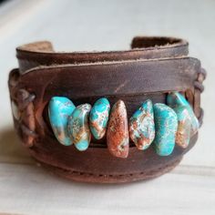 a leather bracelet with turquoise and brown beads on the inside, sitting on a table