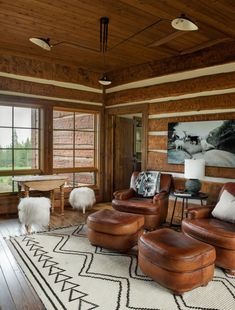 a living room with leather furniture and wood paneling on the walls, along with large windows