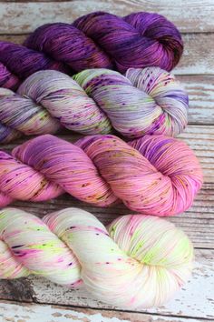 three skeins of yarn sitting next to each other on a wooden surface,