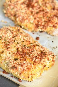 two pieces of food sitting on top of a baking sheet covered in cheese and seasoning