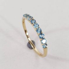 This stunning ring is set in 14k Solid Yellow Gold with Natural Swiss Blue Topaz with utmost precision. It is an unique statement gemstone ring for nearly every occasion and is completely hassle-free jewelry. ITEM DETAILS: * GEM: Swiss Blue Topaz * GEM SIZE: 2mm * GEM SHAPE: Round 9pcs * Gem weight: 0.47 carats * Gold Purity: 14KT * Gold Weight: 0.89 gram * Total Weight of the Ring: 0.98 gram The Gold purity is guaranteed and it comes with an authentic 14KT gold hallmark. Since my items are hand Elegant Stackable Blue Topaz Ring, Elegant Blue Topaz Stackable Rings With Gemstones, Elegant Blue Topaz Gemstone Stackable Rings, Blue Topaz Birthstone Ring For Anniversary, Anniversary Blue Topaz Birthstone Ring, Fine Jewelry Blue Topaz Gemstone Stackable Rings, Yellow Gold Blue Topaz Round Band Rings, Stackable Blue Topaz Ring In Fine Jewelry Style, Stackable Blue Topaz Ring Fine Jewelry