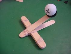 an airplane made out of popsticks and a ball on a green table top