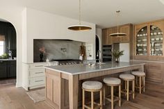 a kitchen with an island and stools in front of the counter top, surrounded by wooden cabinets