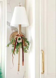 a christmas wreath hanging from the side of a white wall next to a light fixture