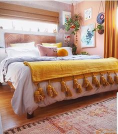 a bedroom with a bed, rugs and pictures on the wall above it that has yellow tassels hanging from the headboard