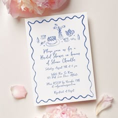 the wedding card is next to some pink flowers and peonies on the table