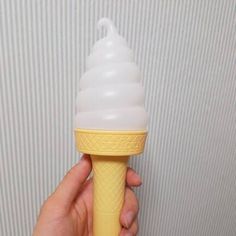 a hand holding an ice cream cone in front of a wall