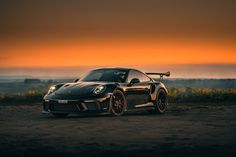 a black sports car parked in front of a sunset