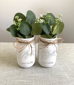 two mason jars with flowers in them on a table