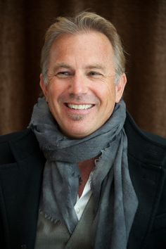 a smiling man wearing a gray scarf and black jacket