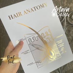 a person holding up a piece of paper with gold foil on it that says hair anatomy