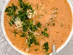 a white bowl filled with soup and garnished with parmesan cheese