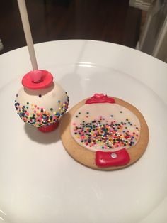 two decorated cookies sitting on top of a white plate covered in sprinkles