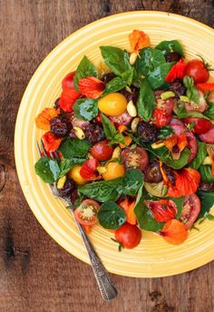 a yellow plate filled with lots of different types of vegetables on top of a wooden table