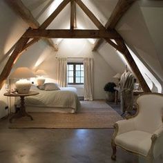 an attic bedroom with white walls and wood beams