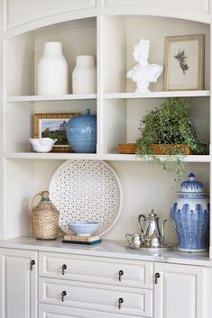 a white shelf with vases and pictures on it