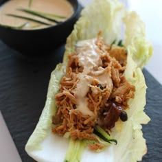 lettuce with meat and sauce sitting on a plate next to a dipping sauce