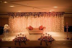 a couch sitting on top of a white table covered in flowers and candles next to a wall