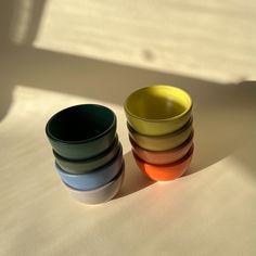 four bowls are stacked on top of each other in different colors and sizes, with one sitting next to the other