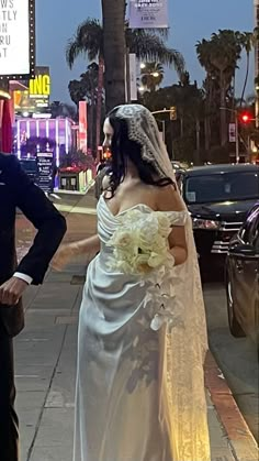 a bride and groom are standing on the sidewalk in front of a movie theater at night