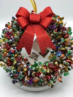 a christmas wreath ornament with a red bow hanging from it's side