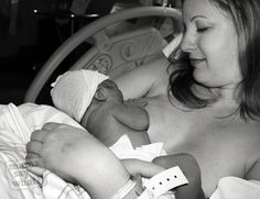 a black and white photo of a woman holding a baby in her arms while laying in a hospital bed