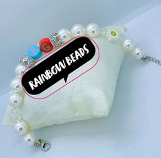 a white bag with some beads on it and the words rainbow beads written in black