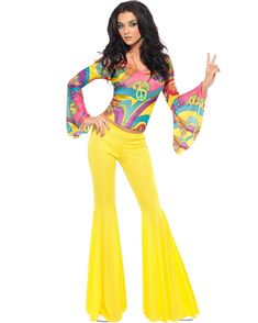 a woman in yellow pants and a colorful top is posing for the camera with her hands up