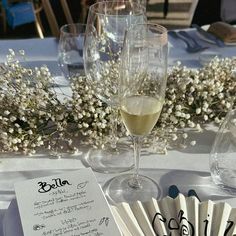 a table topped with wine glasses filled with white wine and paper fans next to each other